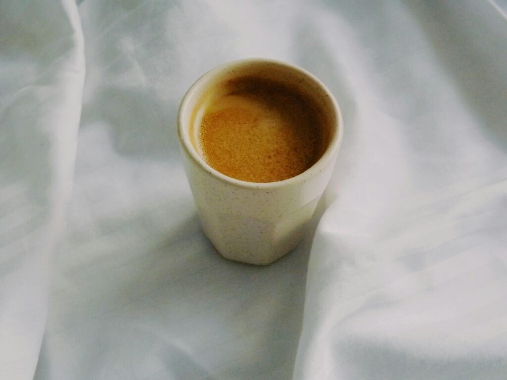 a cup of coffee on a white bedsheet