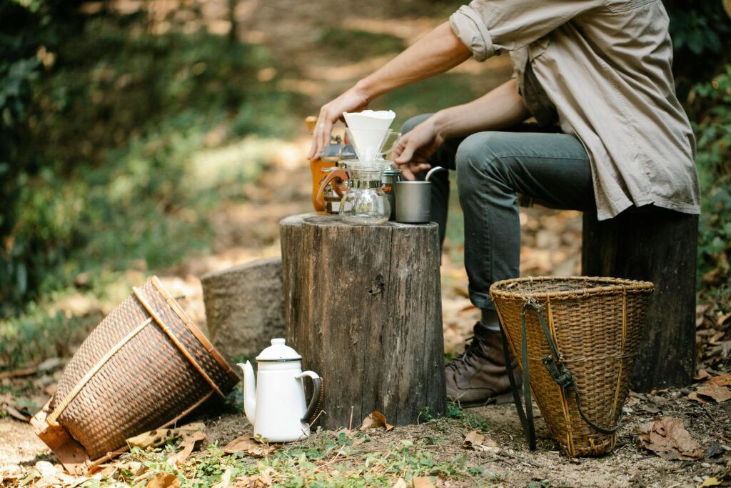 A man preparing coffee in nature on a natural wooden log.